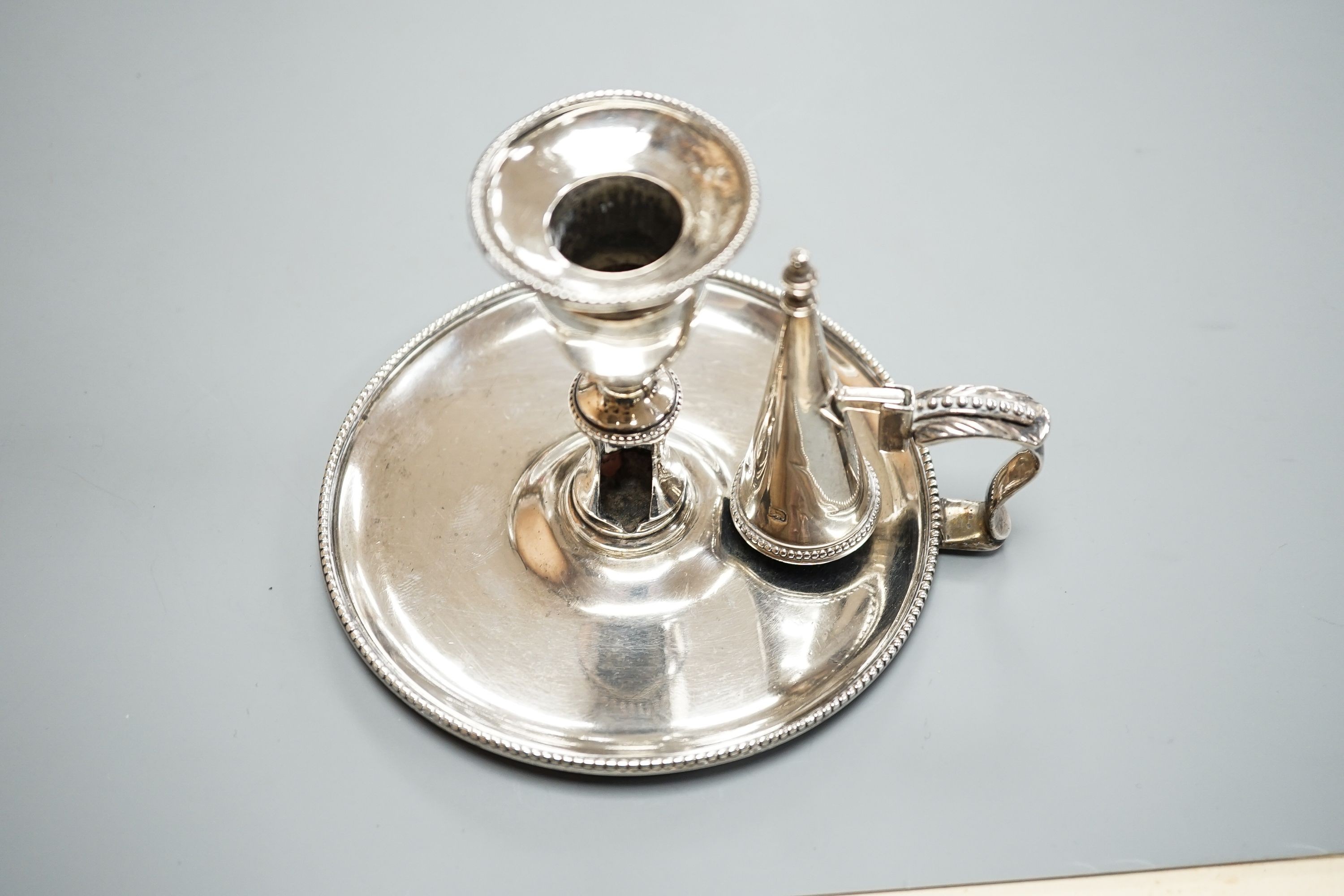 A George III silver chamberstick, by John Arnell, with beaded border and matching sconce and snuffer, London, 1784, diameter 12.8cm, 8oz (a.f.).